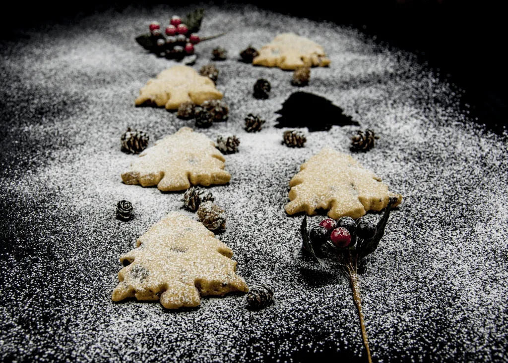 Don't these Christmas tree shortbreads look delicious. Icing sugar snow and Christmas decorations. Pack them up in Christmas wrapping or present them to be munched on at any time. A very simple Christmas recipe. Yum | theyumyumclub.com