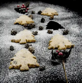 Don't these Christmas tree shortbreads look delicious. Icing sugar snow and Christmas decorations. Pack them up in Christmas wrapping or present them to be munched on at any time. A very simple Christmas recipe. Yum | theyumyumclub.com