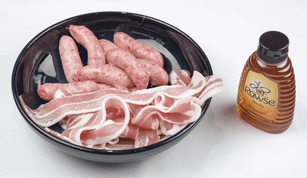 Pigs in blankets. Little pork chipolatas, wrapped in streaky bacon, and smothered in honey. The perfect accompaniment to Christmas Turkey. Yum! | theyumyumclub