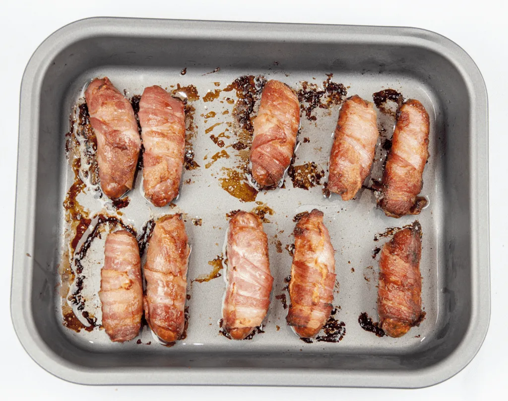 Pigs in blankets. Little pork chipolatas, wrapped in streaky bacon, and smothered in honey. The perfect accompaniment to Christmas Turkey. Yum! | theyumyumclub