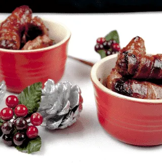 Pigs in blankets. Little pork chipolatas, wrapped in streaky bacon, and smothered in honey. The perfect accompaniment to Christmas Turkey. Yum! | theyumyumclub