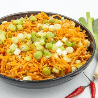 This spicy carrot, sesame and scallion salad is so simple and so healthy. 3 ingredients for the salad, 4 ingredeints for the spicy dressing, and just over 200 calories per bowl. Yum! | theyumyumclub.com