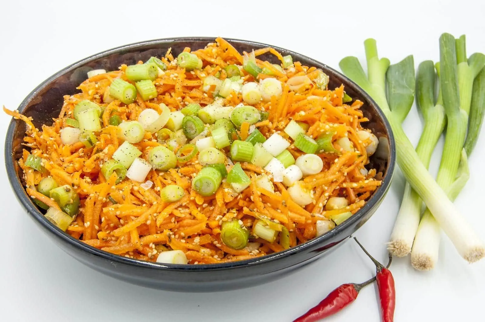 This spicy carrot, sesame and scallion salad is so simple and so healthy. 3 ingredients for the salad, 4 ingredeints for the spicy dressing, and just over 200 calories per bowl. Yum! | theyumyumclub.com