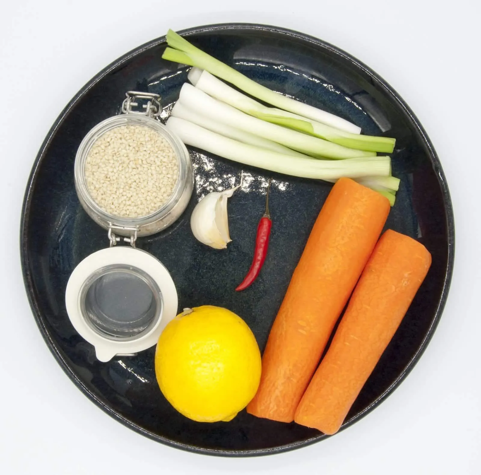 This spicy carrot, sesame and scallion salad is so simple and so healthy. 3 ingredients for the salad, 4 ingredeints for the spicy dressing, and just over 200 calories per bowl. Yum! | theyumyumclub.com