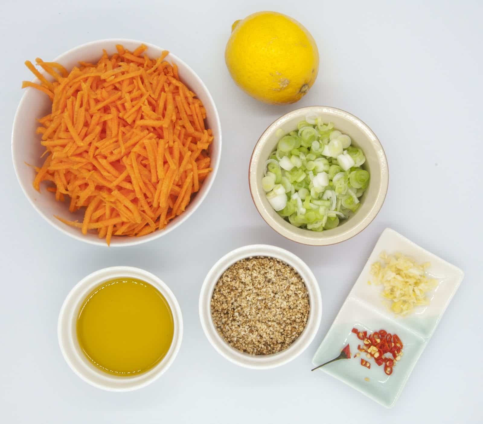This spicy carrot, sesame and scallion salad is so simple and so healthy. 3 ingredients for the salad, 4 ingredeints for the spicy dressing, and just over 200 calories per bowl. Yum! | theyumyumclub.com