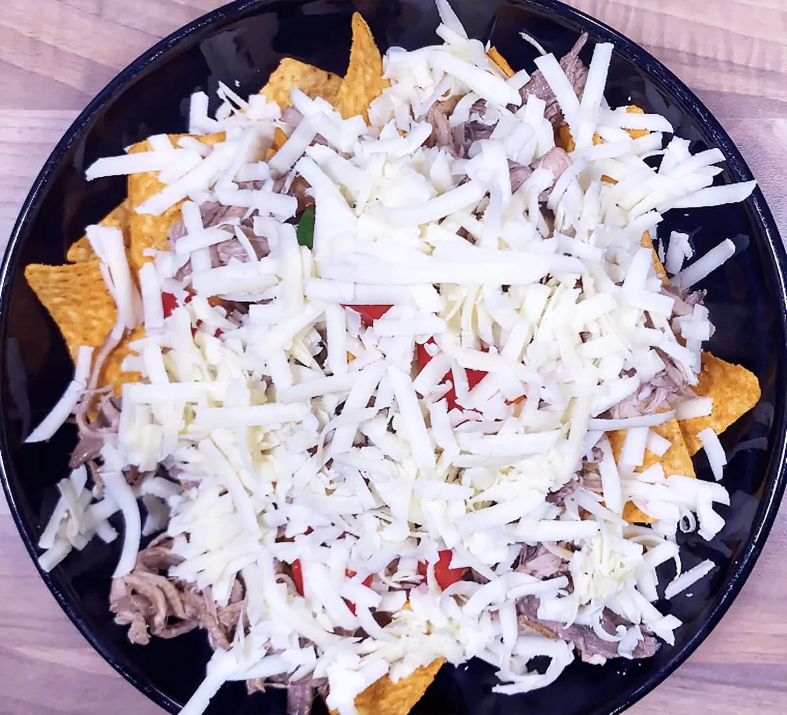 We all know pulled pork nachos but how about tangy pulled pork shoulder Doritos! Tangy cheese Doritos covered in spicy slow-cooked pork shoulder drowned in melted cheddar cheese. Yum! | theyumyumclub.com
