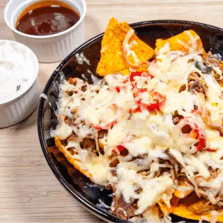 We all know pulled pork nachos but how about tangy pulled pork shoulder Doritos! Tangy cheese Doritos covered in spicy slow-cooked pork shoulder drowned in melted cheddar cheese. Yum! | theyumyumclub.com