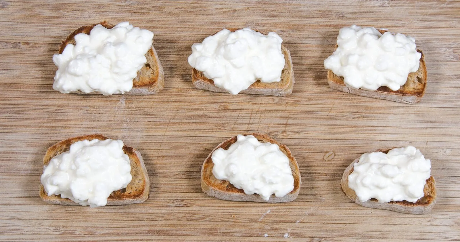 Add the ricotta to the crostini | https://theyumyumclub.com/2019/04/23/ricotta-prosciutto-fig-crostini/