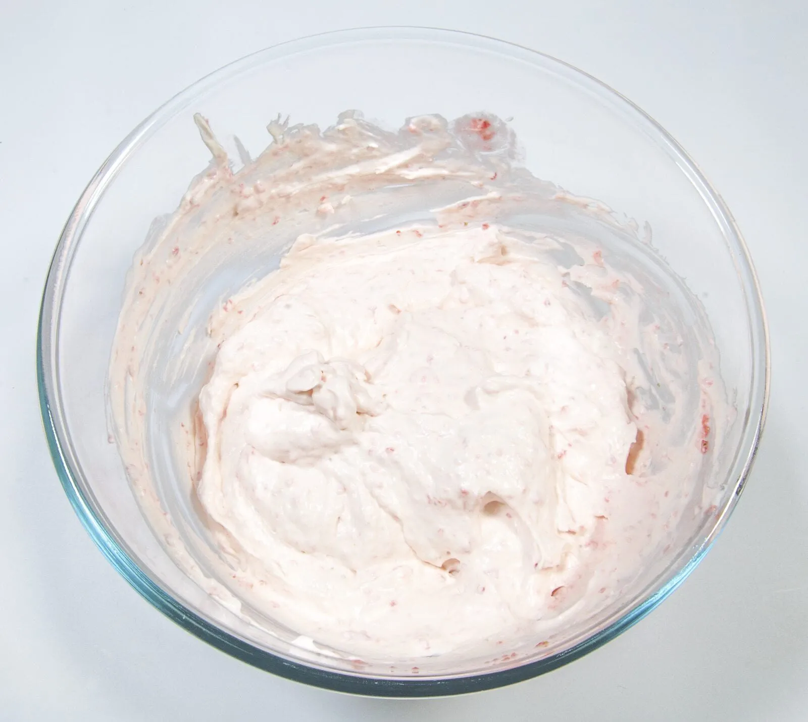 Fluffy and creamy strawberry mousse. Fold the strawberries into the cream. | https://theyumyumclub.com/2019/05/10/fluffy-creamy-strawberry-mousse/