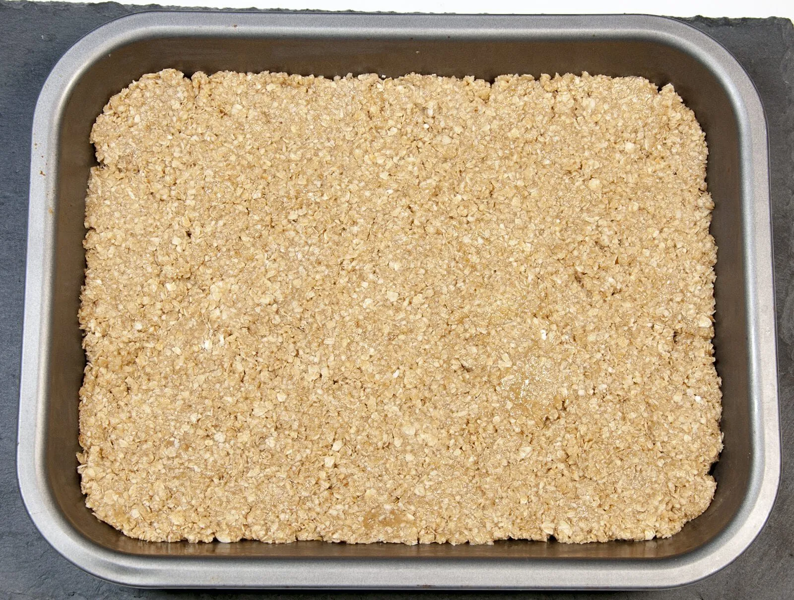 Flatten the flapjack mixture | https://theyumyumclub.com/2019/06/01/extra-soft-and-chewy-flapjacks/