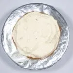 Spread half the icing. Humble Hummingbird Cake With Sweet Pecan Dust | https://theyumyumclub.com/2019/06/05/humble-hummingbird-cake-sweet-pecan-dust/
