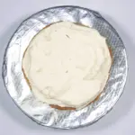 Spread half the icing. Humble Hummingbird Cake With Sweet Pecan Dust | https://theyumyumclub.com/2019/06/05/humble-hummingbird-cake-sweet-pecan-dust/