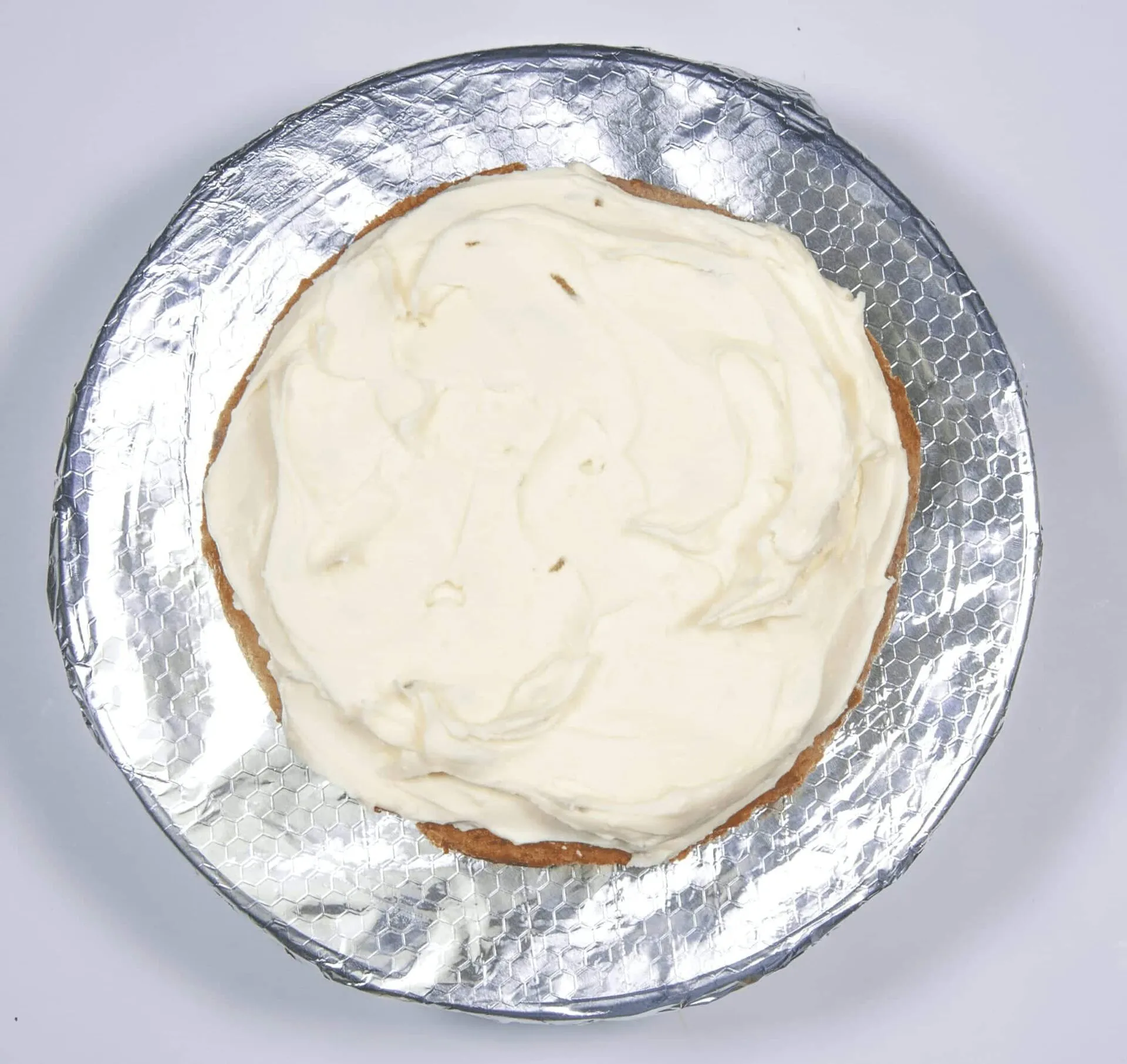 Spread half the icing. Humble Hummingbird Cake With Sweet Pecan Dust | https://theyumyumclub.com/2019/06/05/humble-hummingbird-cake-sweet-pecan-dust/